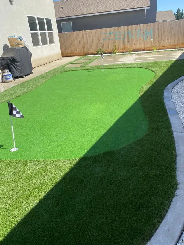 Small backyard putting green with flag in Perris, CA